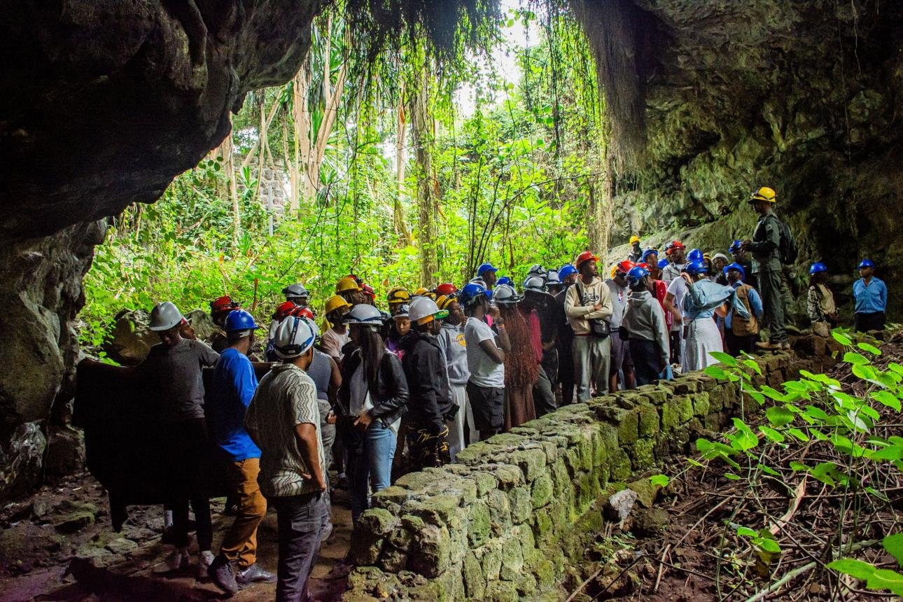 Visitors exploring the dark volcanic passages of Musanze Caves in northern Rwanda.